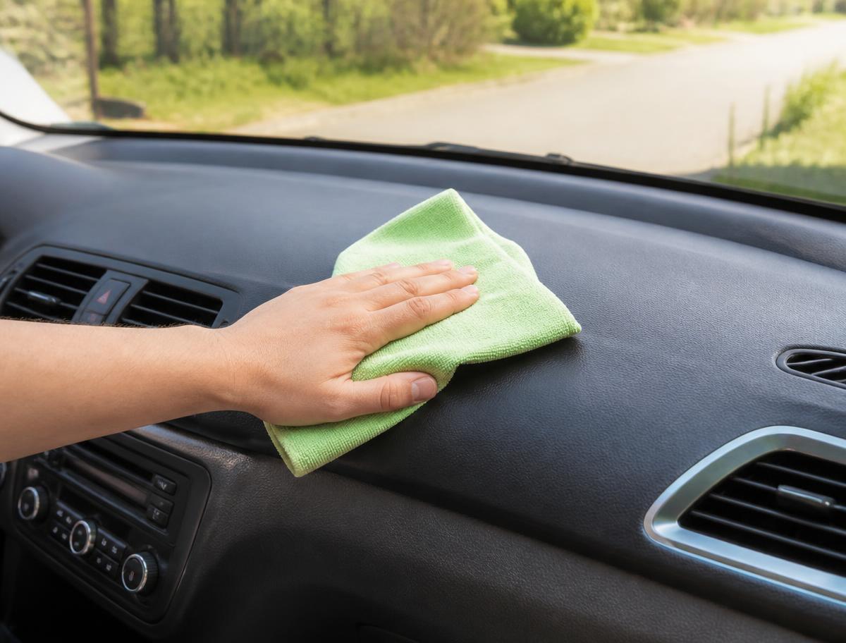 A car dashboard being wiped down with a microfiber cloth
