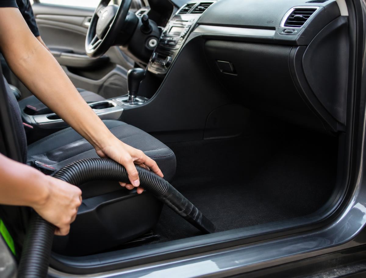 A car interior being vacuumed to clean crumbs and dirt